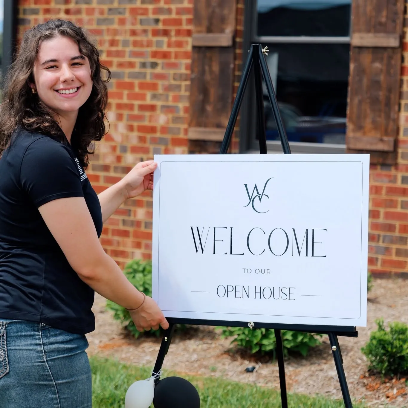 Wright Choice team member smiling beside a welcome sign at an open house