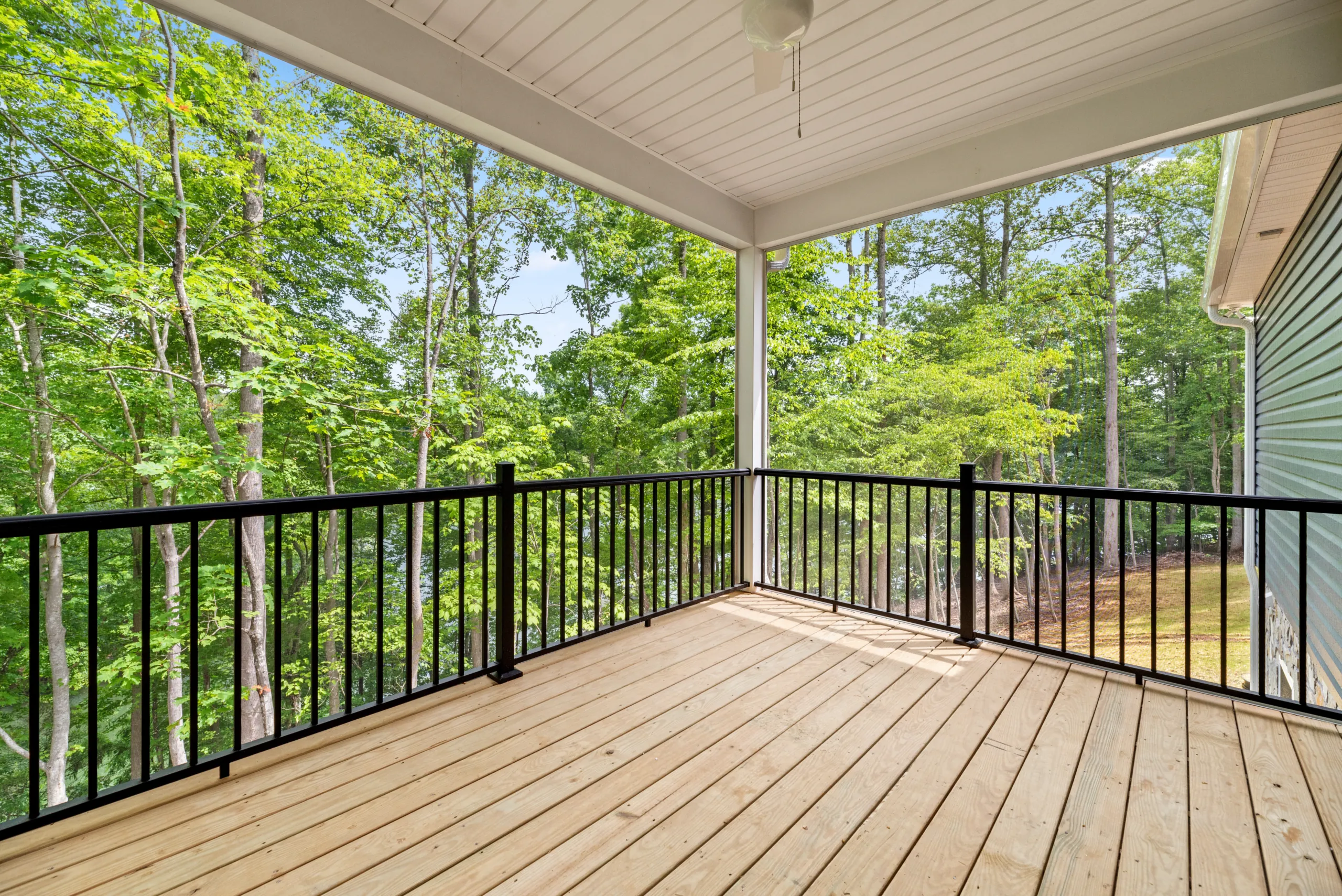 Covered back deck with black metal railing in the Lake Crest Home