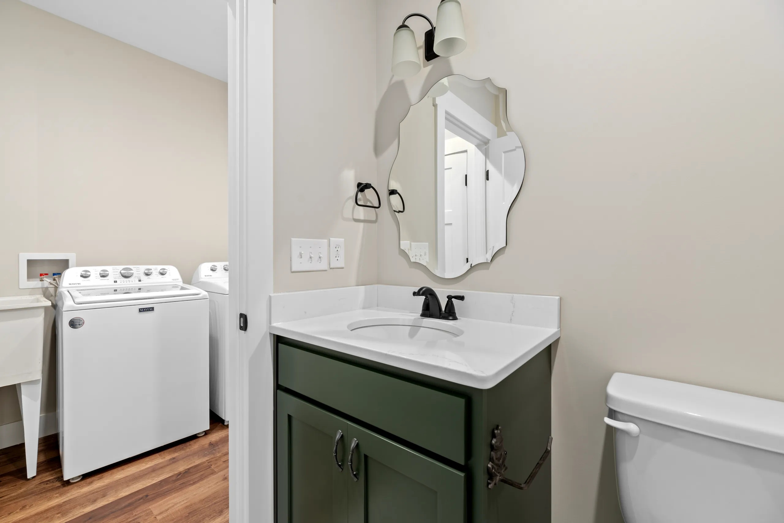 Half bath with green vanity and scalloped mirror in the Lake Crest Home