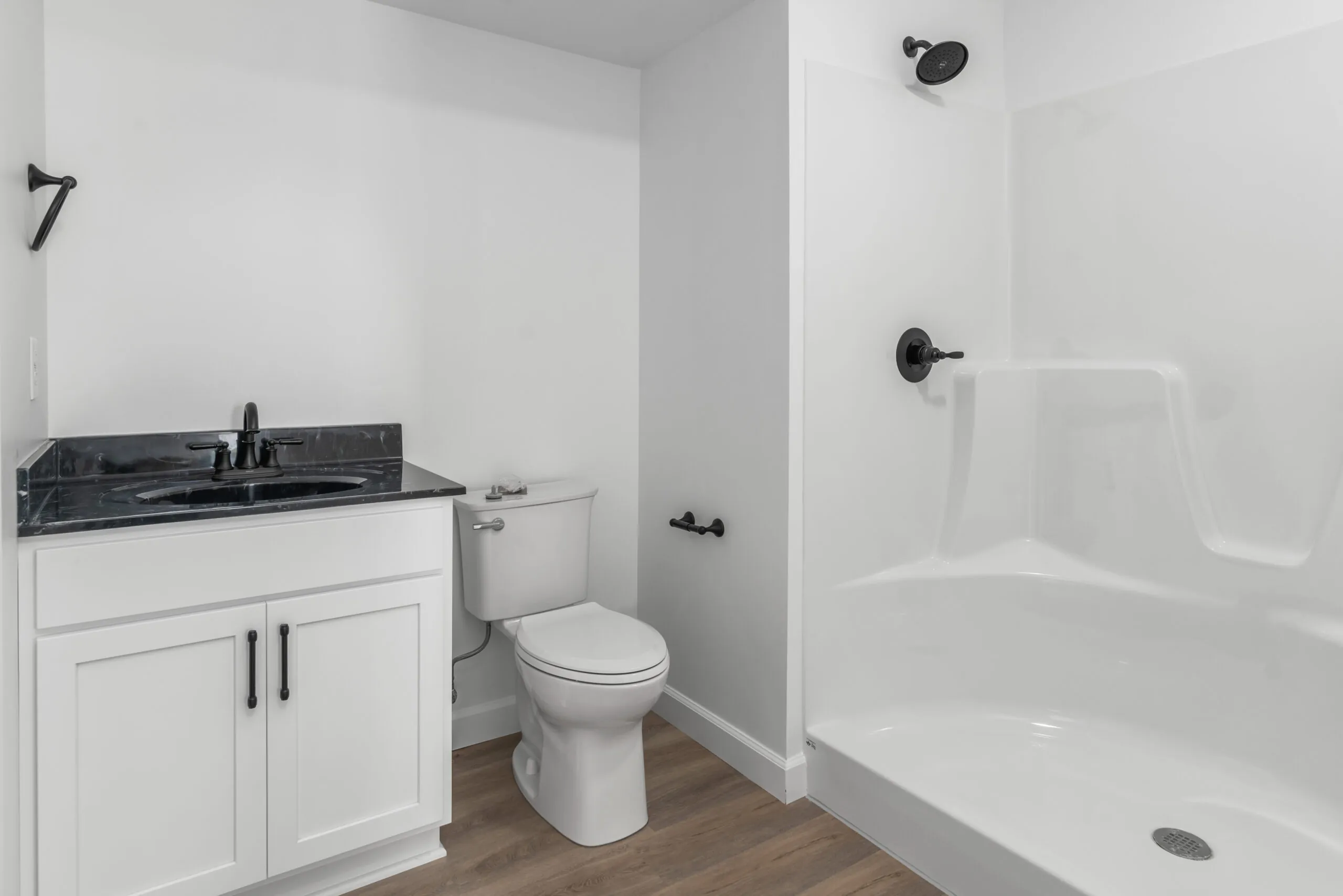 Bathroom with white vanity and black countertop beside a shower in the Otterlea Home