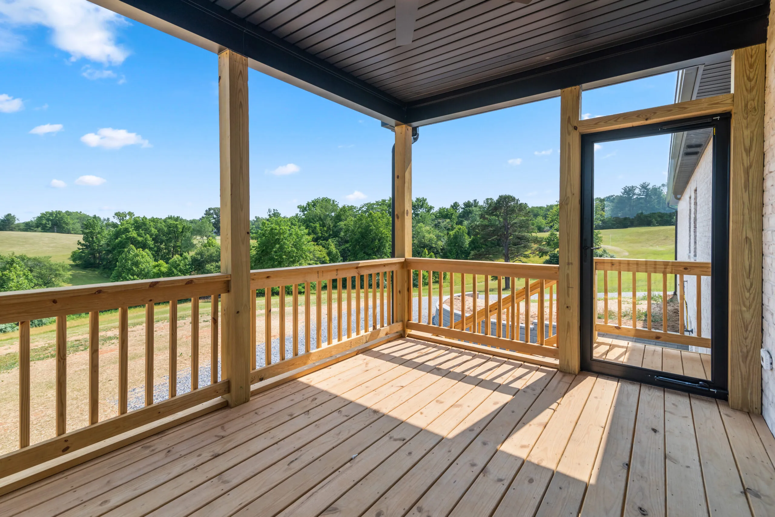 Covered wood porch overlooking pasture at the Otterlea Home
