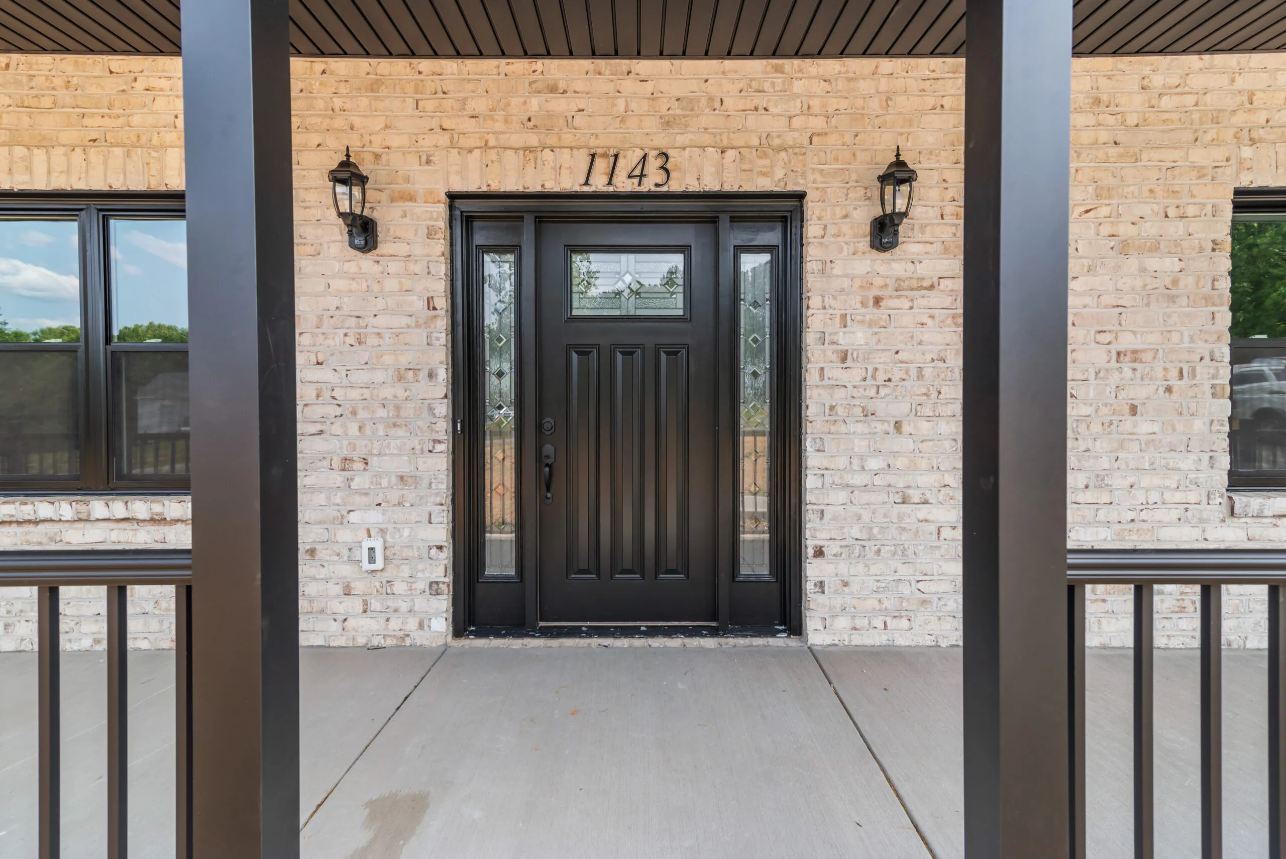 Front entry of the Otterlea Home with black door and light brick