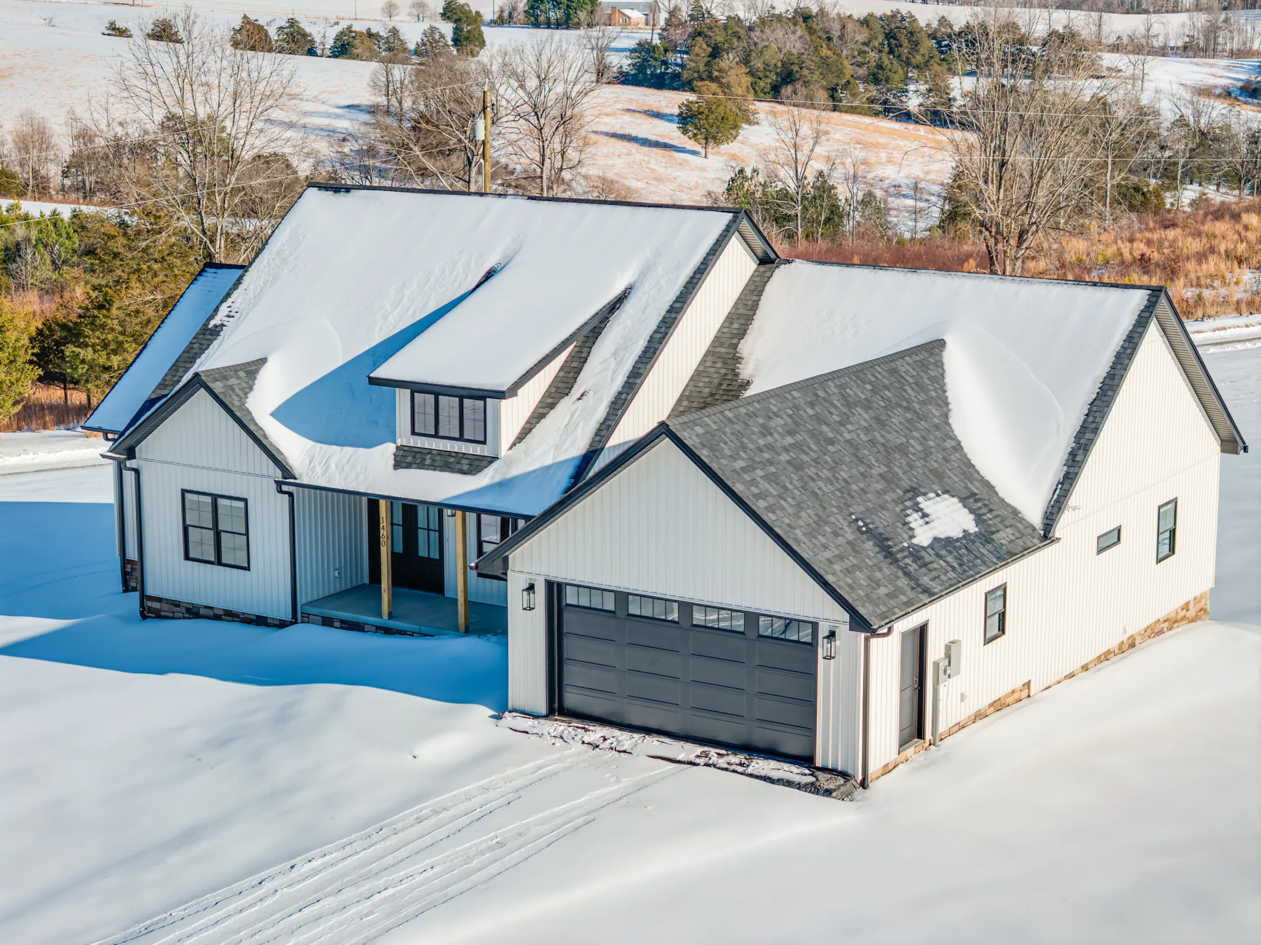 Front of the Powell Lane Home with board-and-batten siding and two-car garage in snow