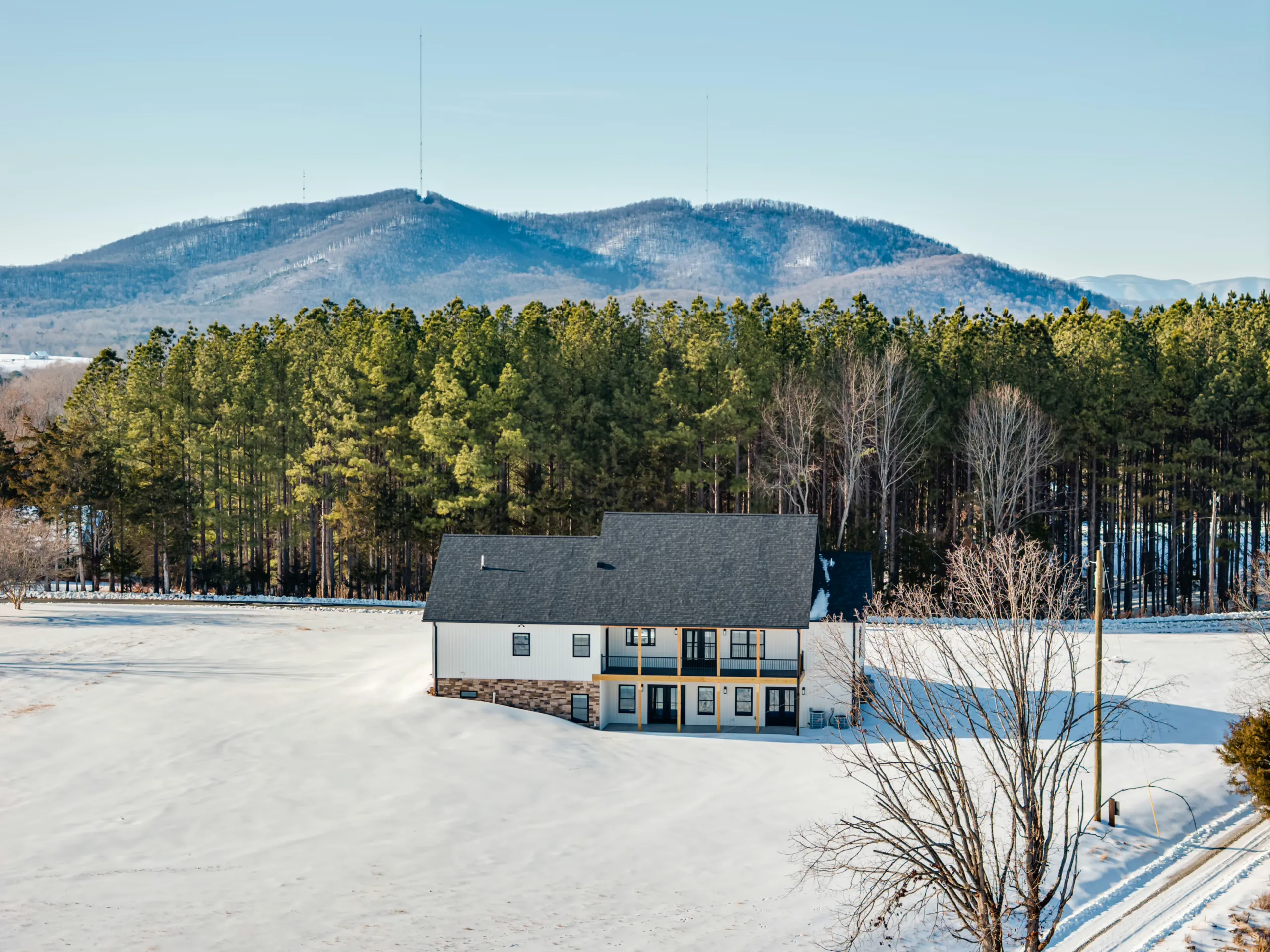 Rear exterior of the Powell Lane Home with mountain view and snow