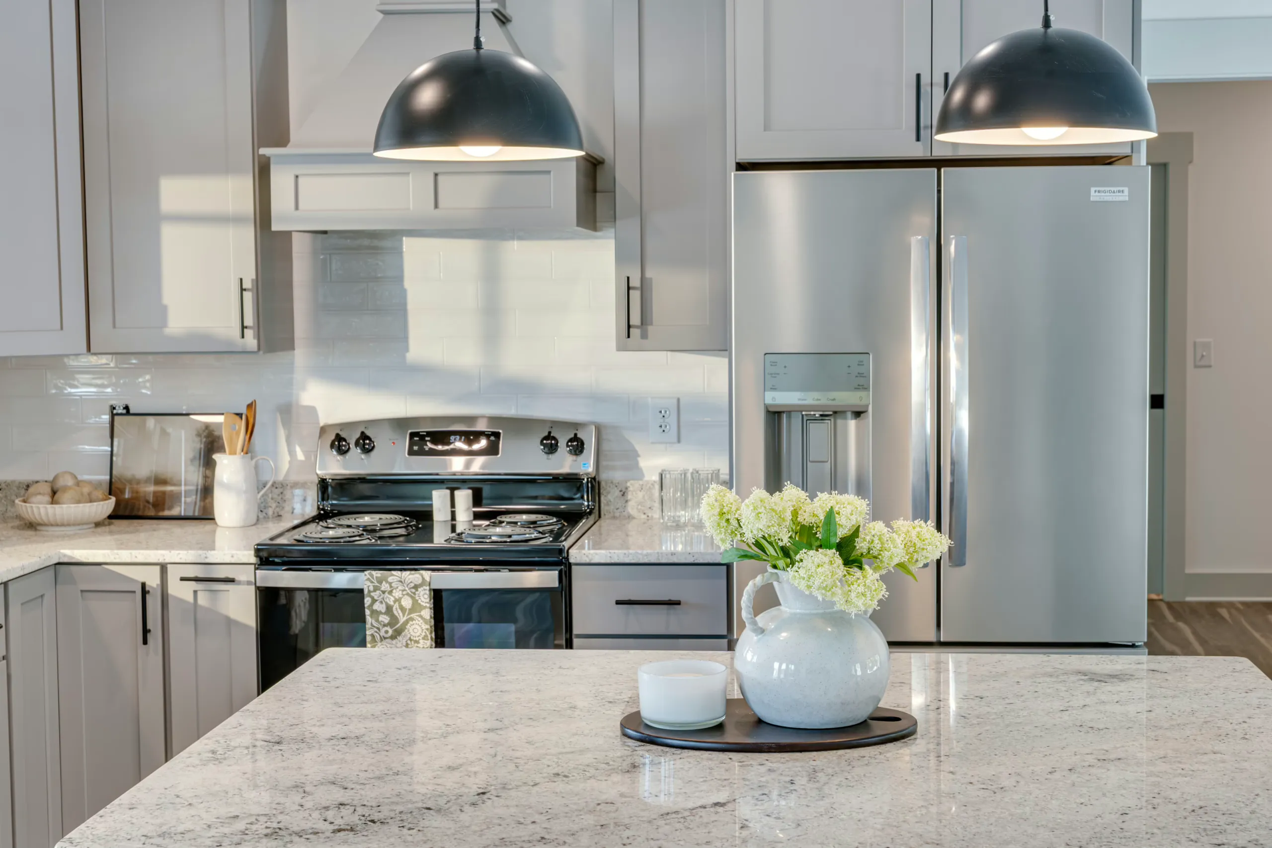 Kitchen range, stainless refrigerator and granite island in the Powell Lane Home