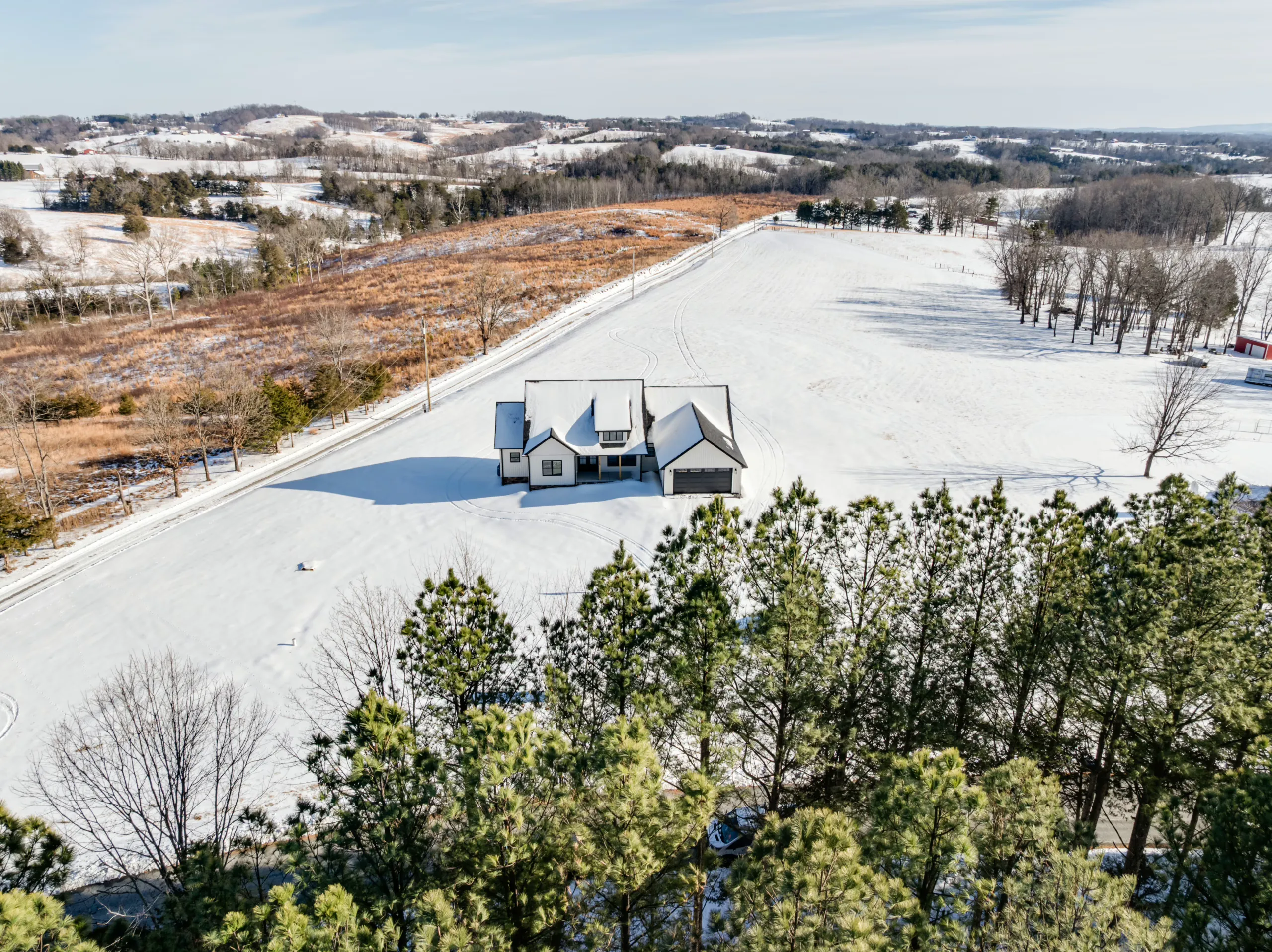 Aerial front view of the Powell Lane Home in snow with open pasture