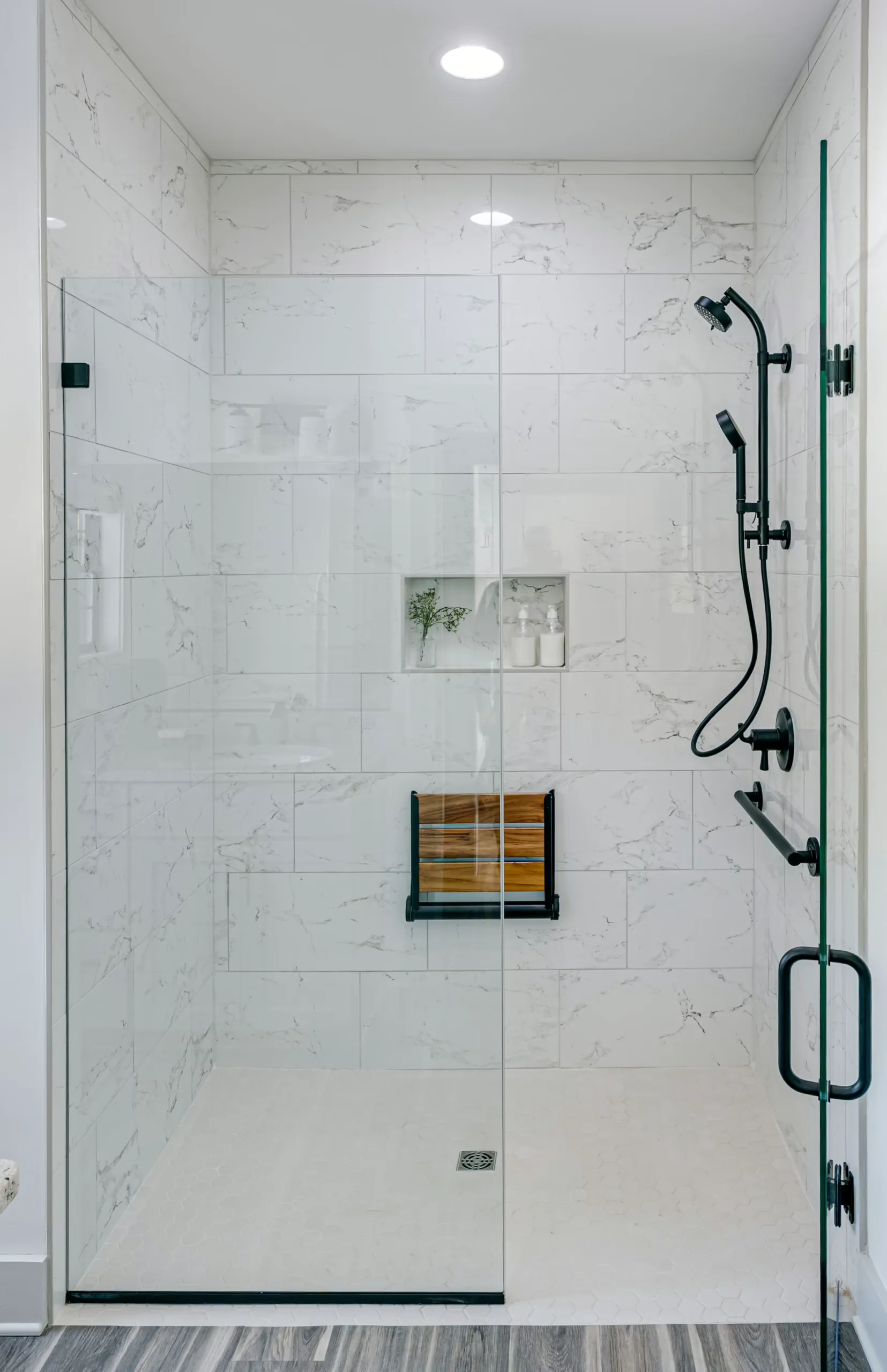 Marble-look tile shower with bench seat and black fixtures in the Powell Lane Home
