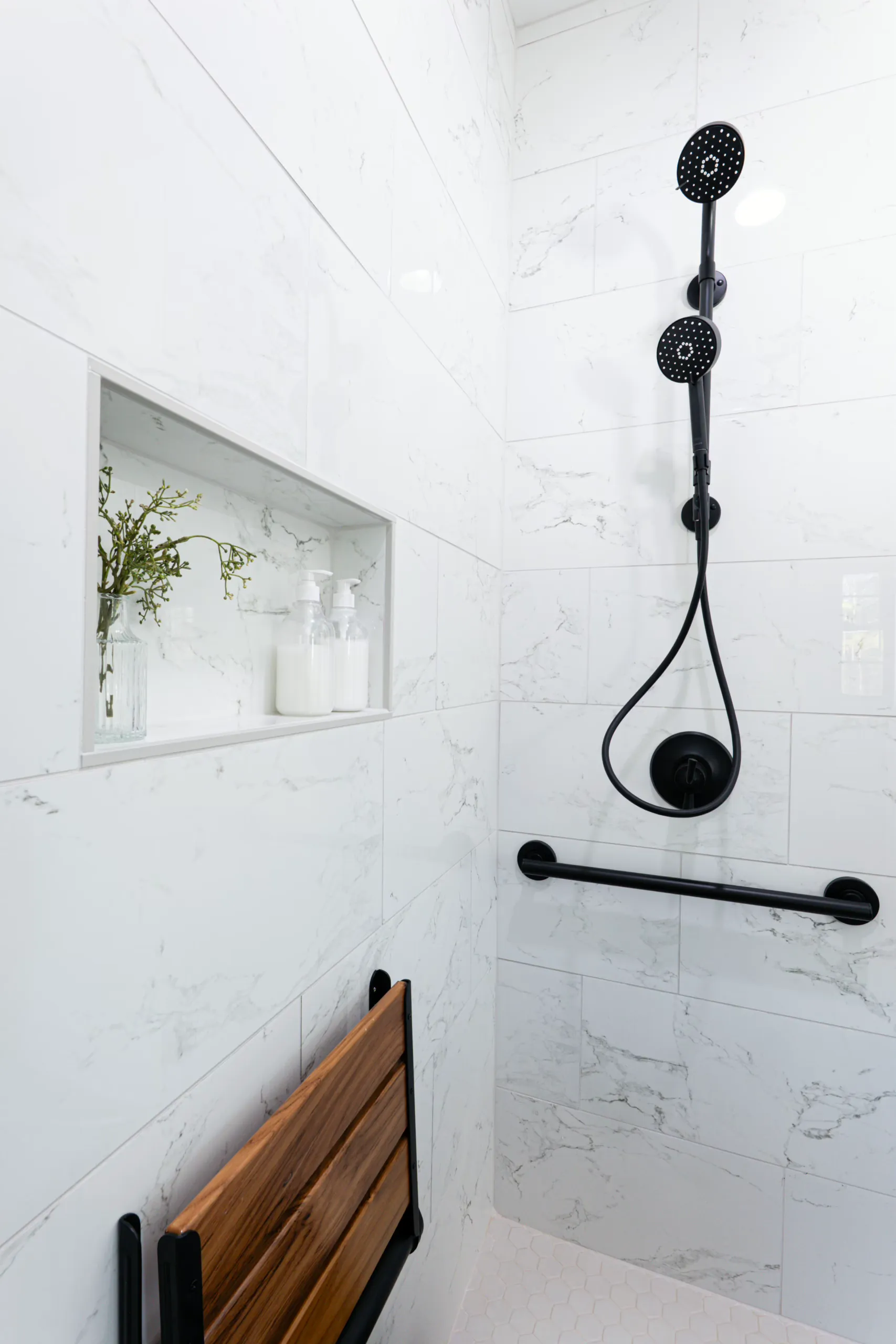 Shower with niche, fold-down teak seat and black fixtures in the Powell Lane Home