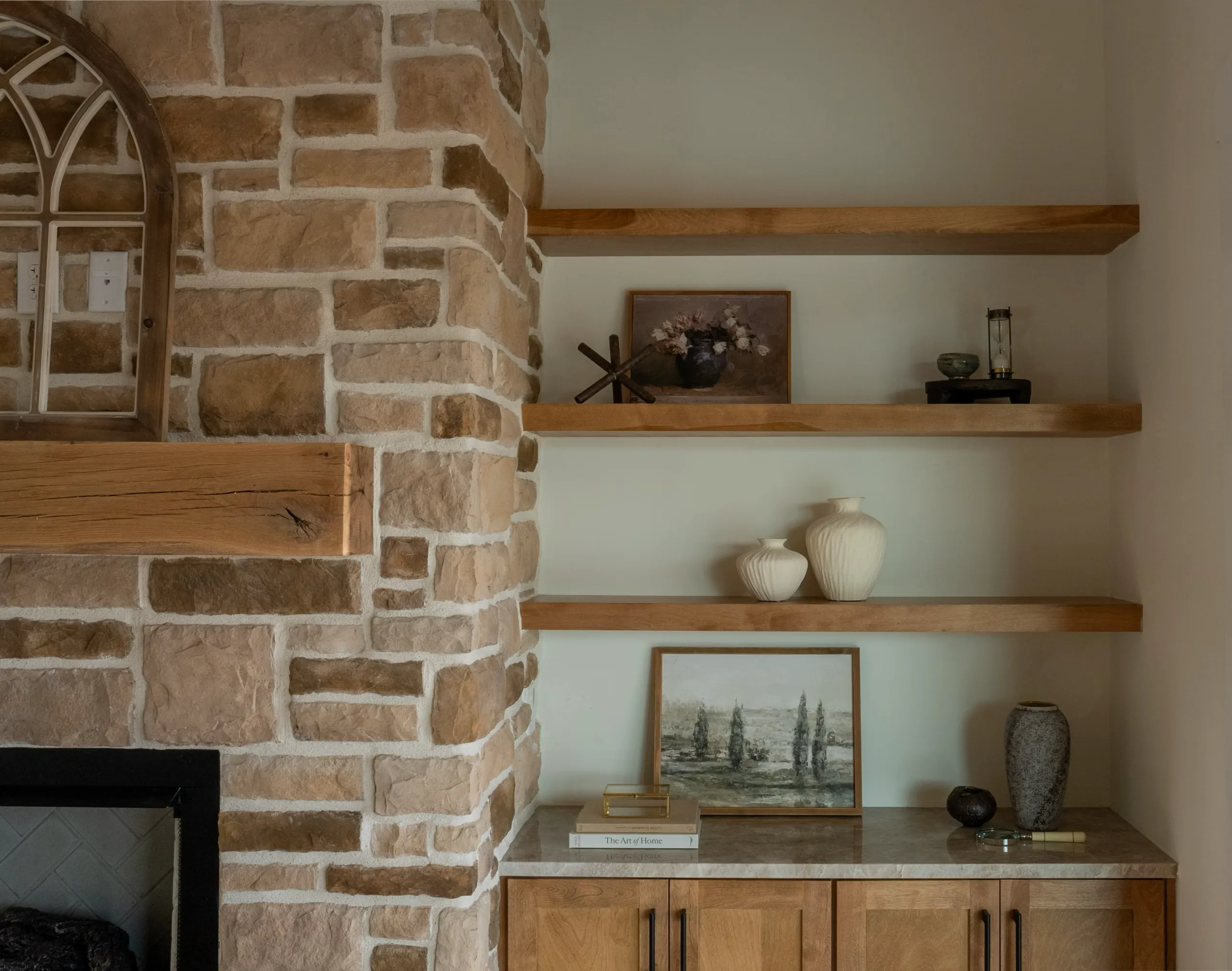 Stone fireplace with floating wood shelves and built-in cabinet in the Magnolia Home
