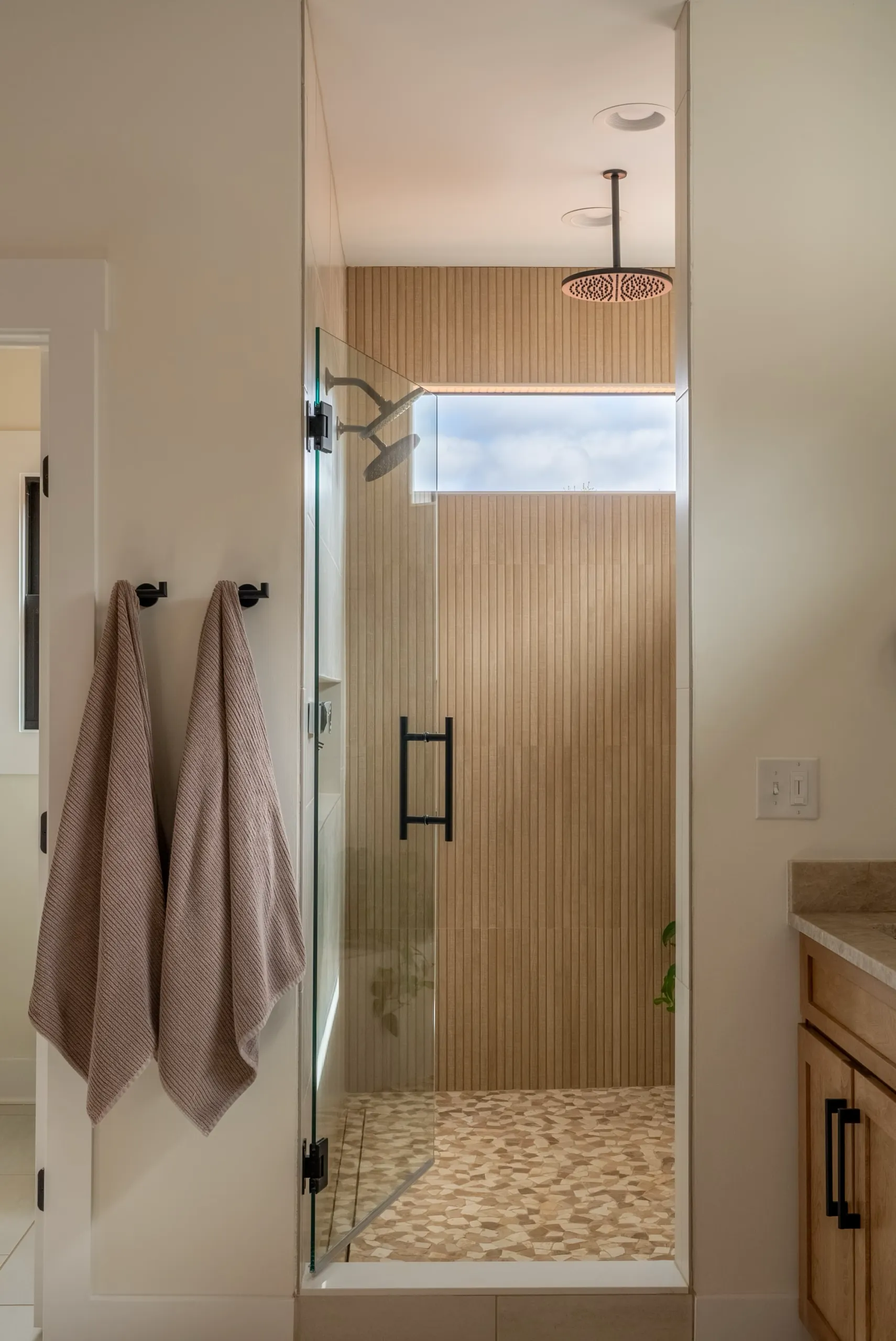 Magnolia Home primary shower with vertical wood-look tile and glass door