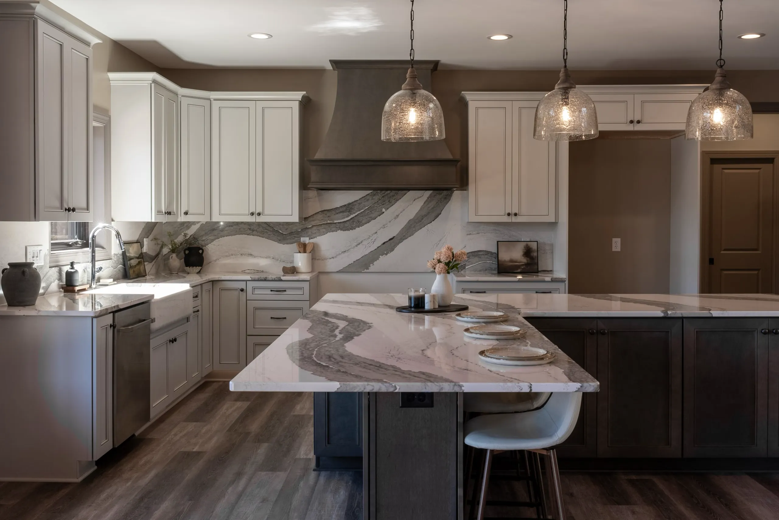 Kitchen in the Waterford Home with gray cabinets, veined quartz island and pendant lights