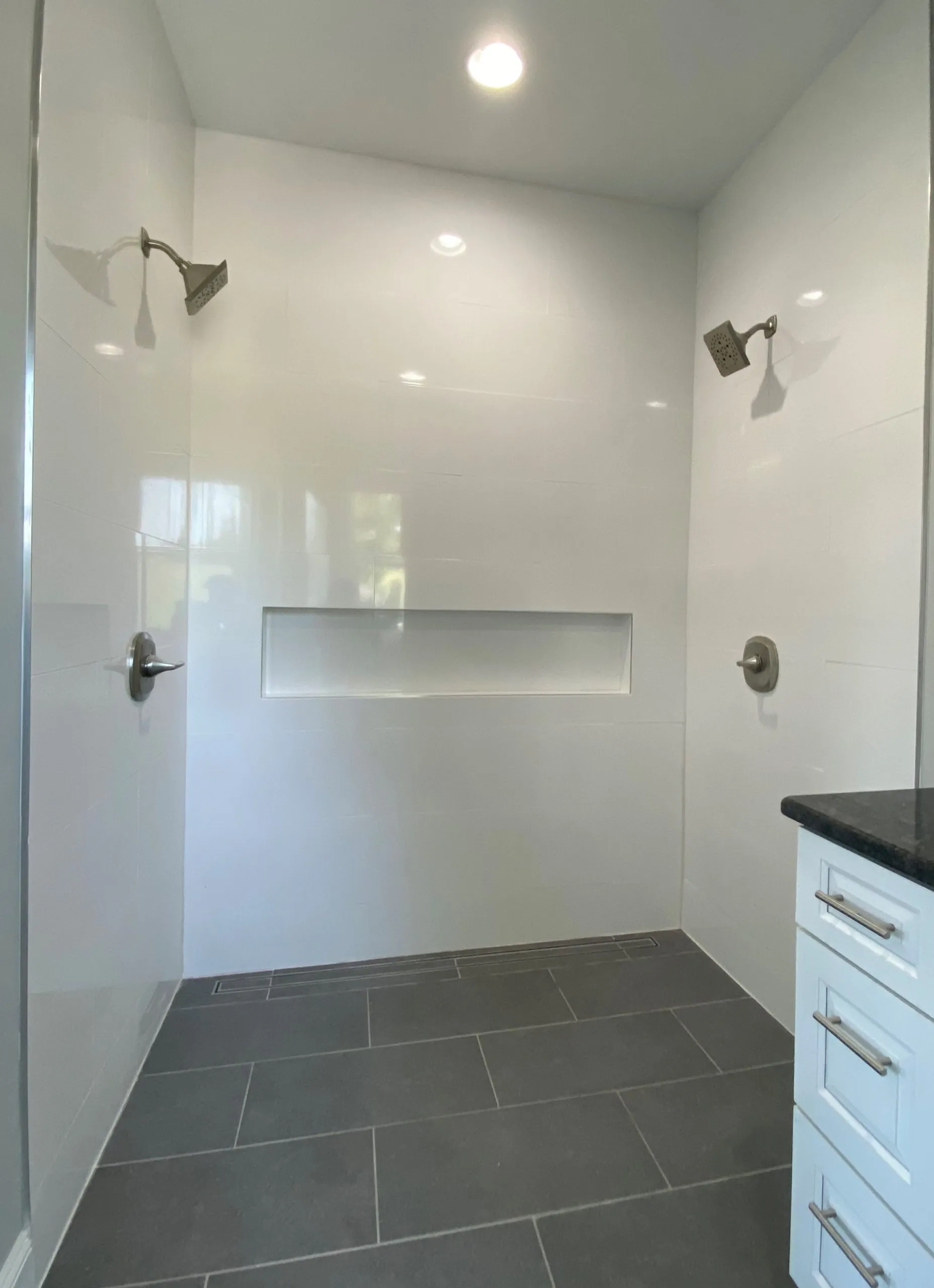 Walk-in tile shower with two shower heads and niche in the Falling Creek Home