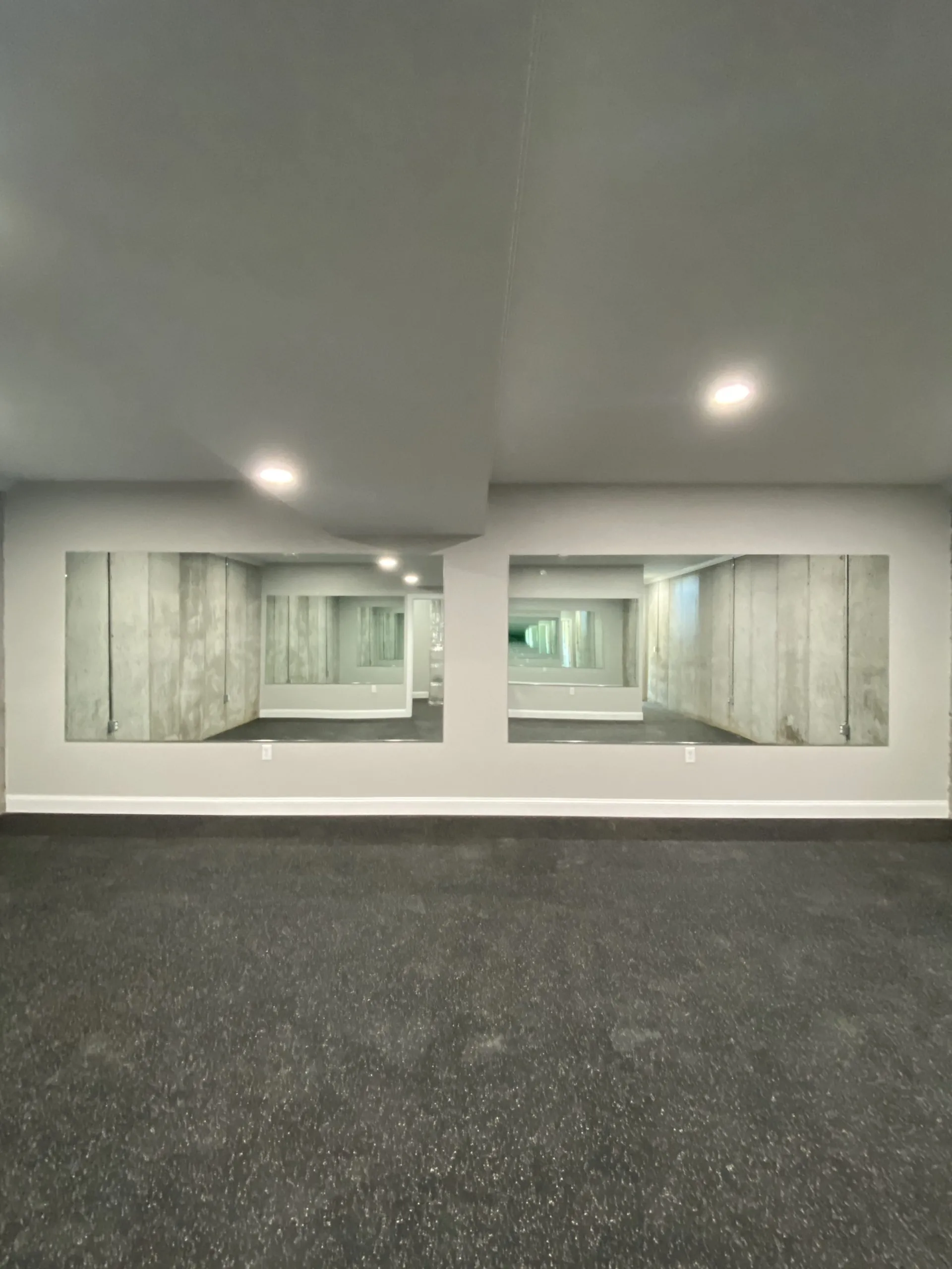 Basement exercise room with wall mirrors and rubber flooring in the Falling Creek Home