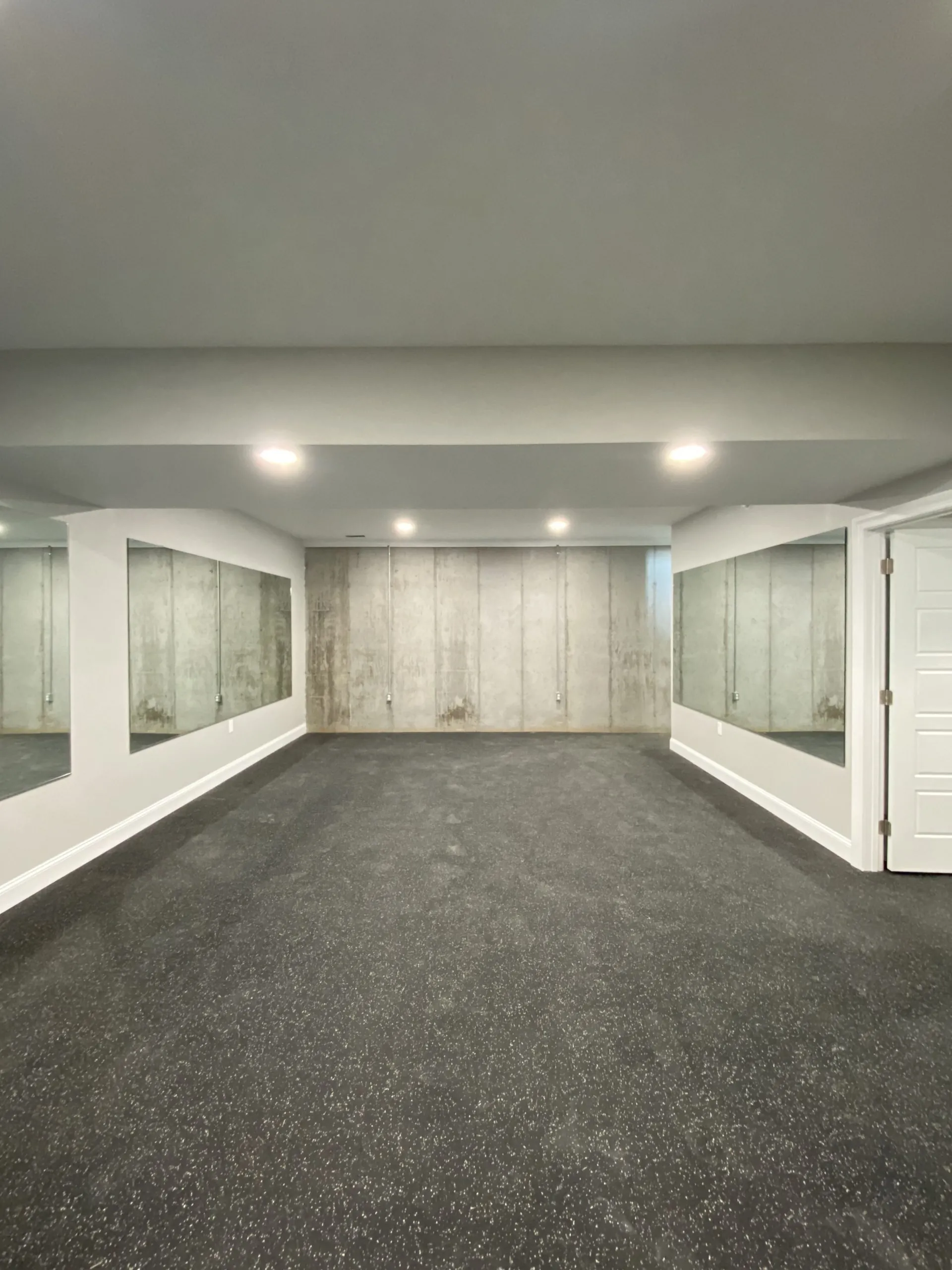 Basement exercise room with wall mirrors and rubber flooring in the Falling Creek Home