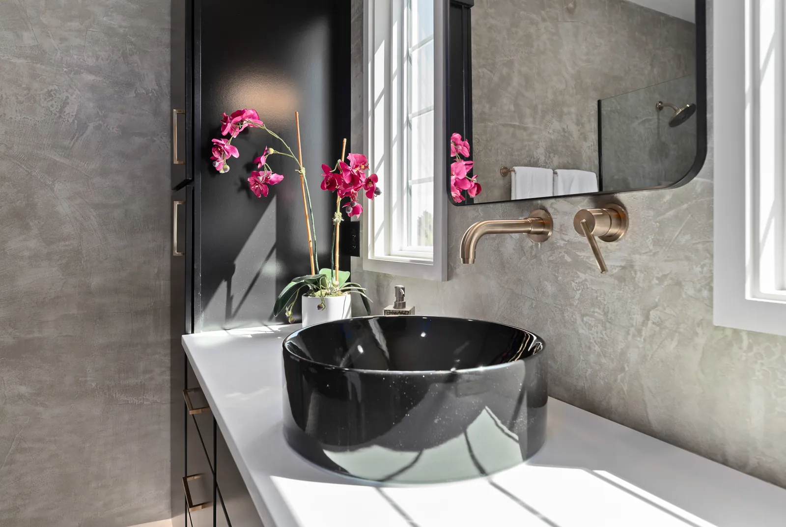 Primary bathroom black vessel sink with brass fixtures in the Otter River Home