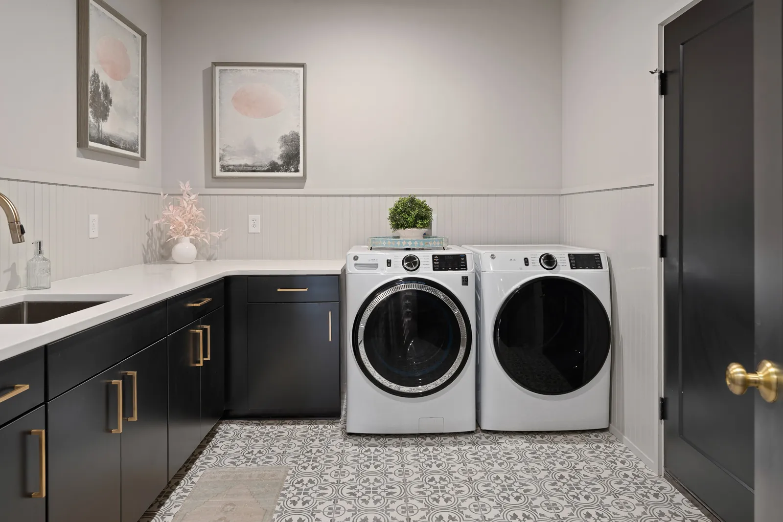 Laundry room with black cabinets and patterned tile floor in the Otter River Home