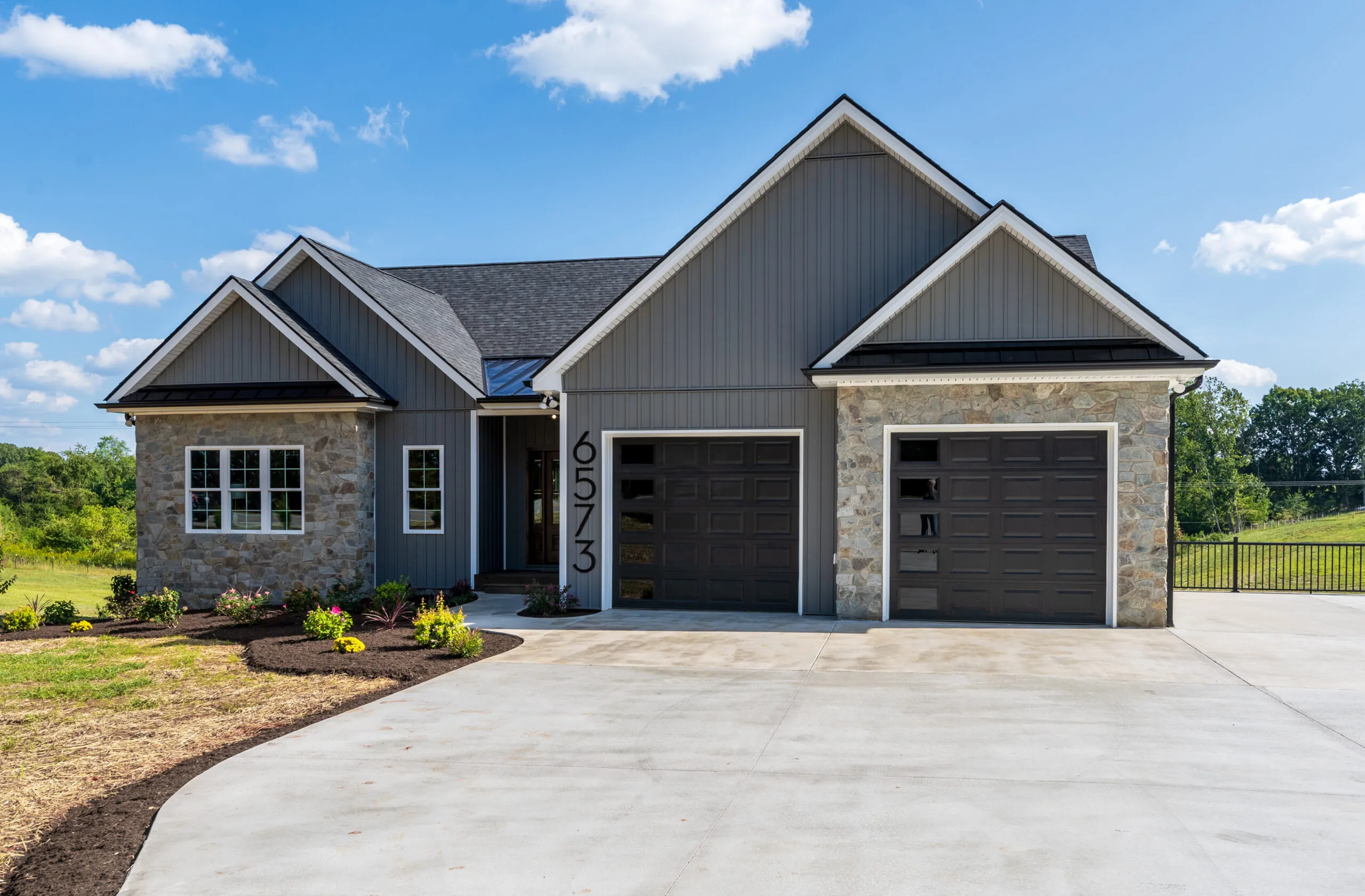 Front of the Otter River Home with gray siding, stone and two-car garage