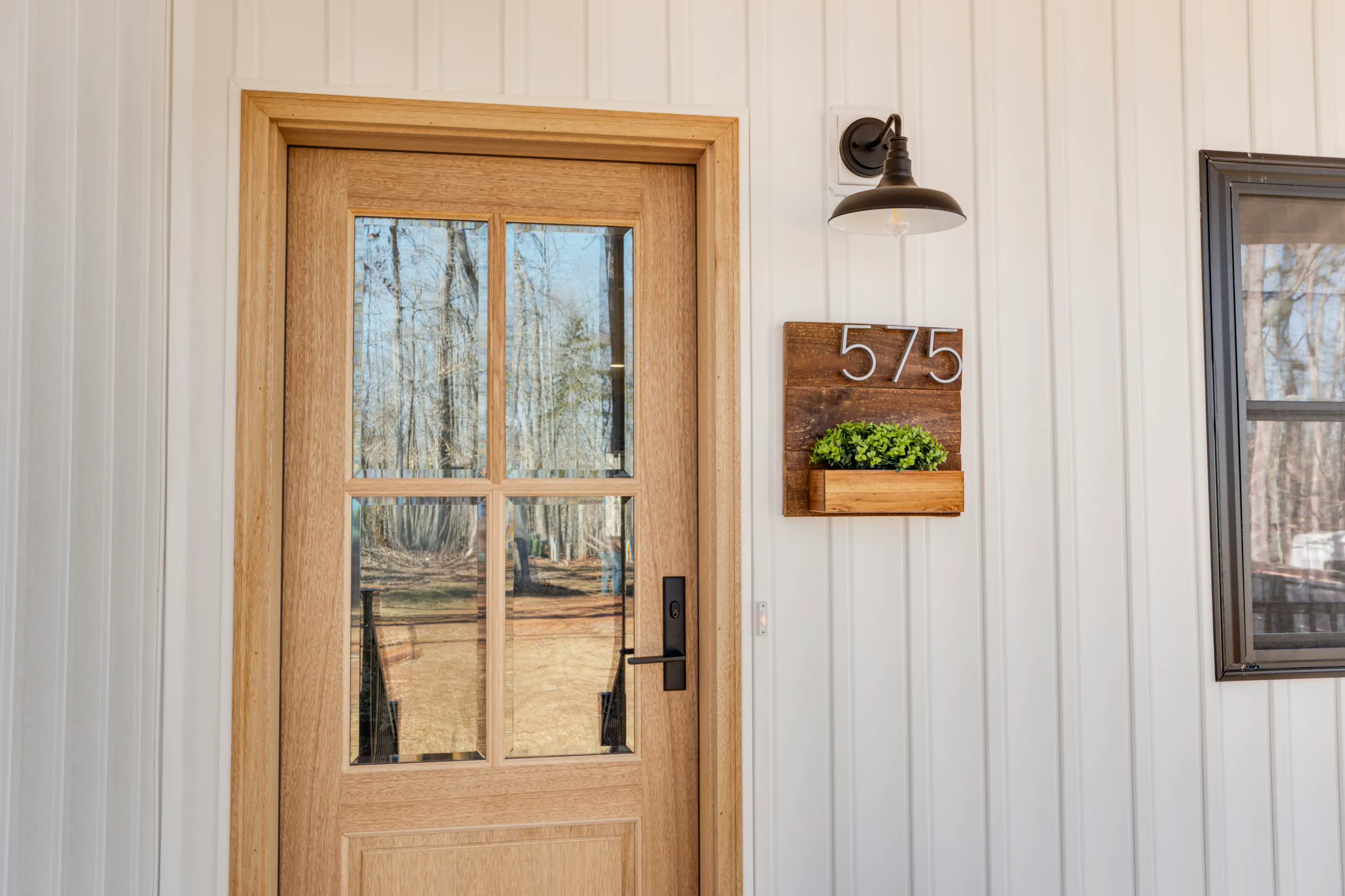 Wood front door with glass panes and house number 575 at the Reservoir Home