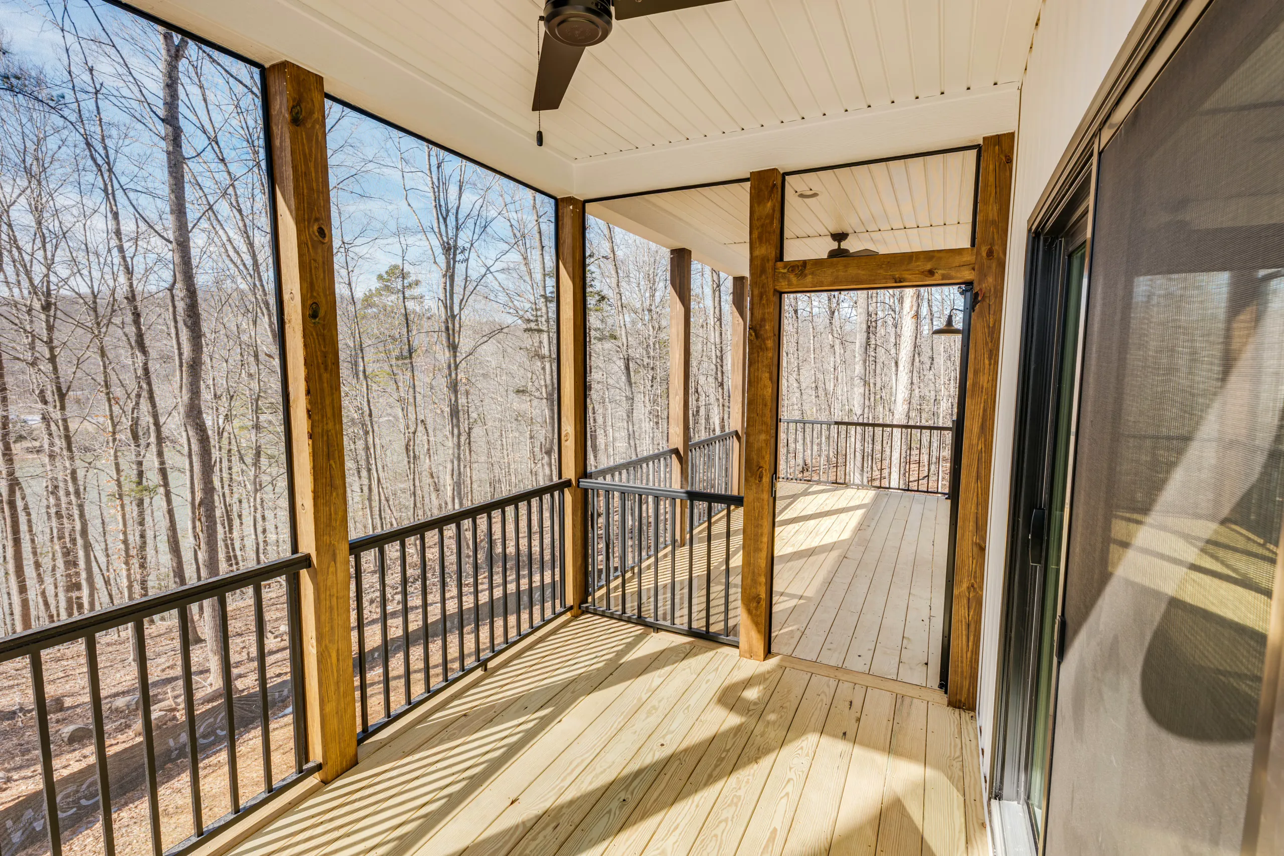 Screened porch with timber posts and black railing at the Reservoir Home