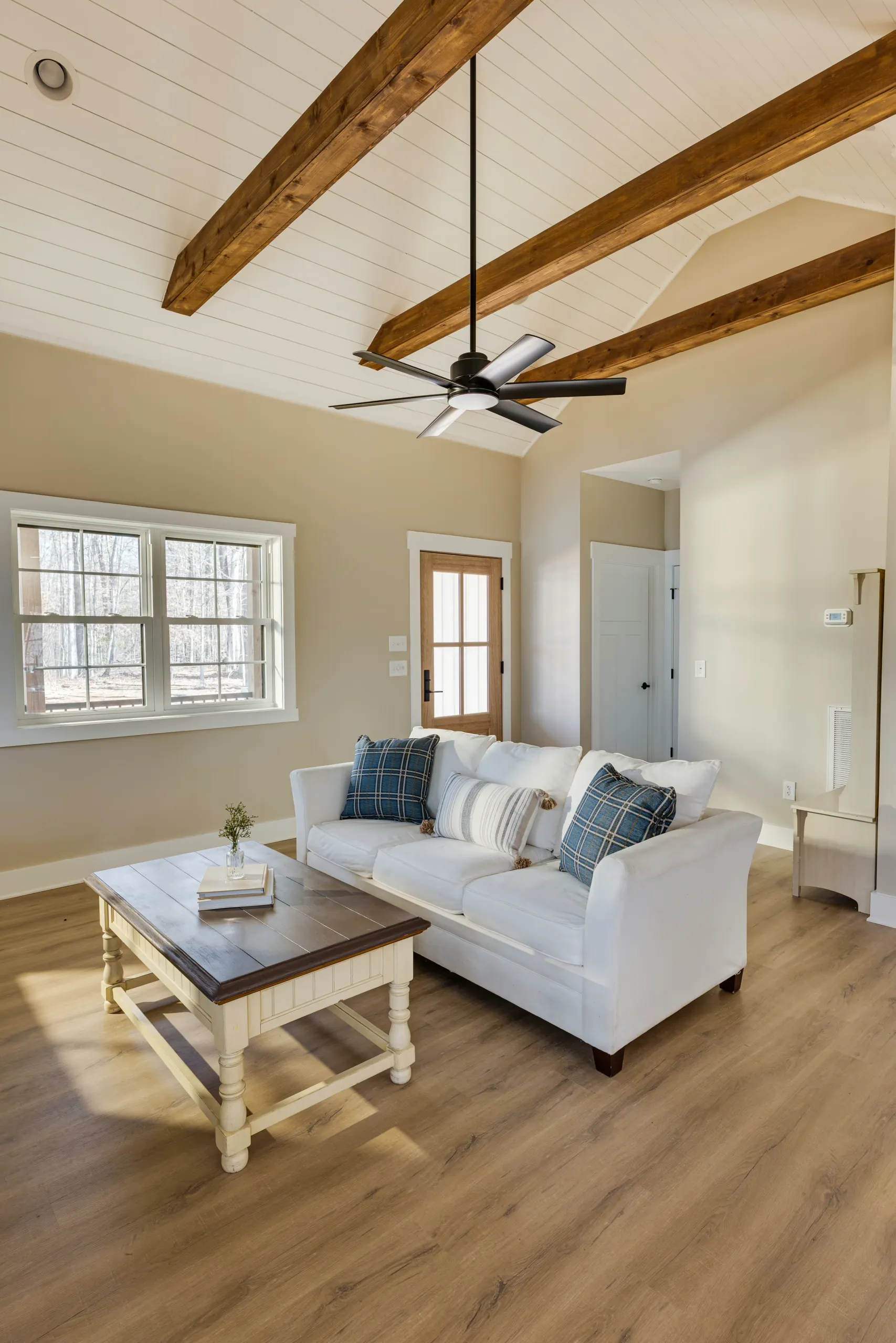 Living room with exposed beams, shiplap ceiling and white sofa in the Reservoir Home