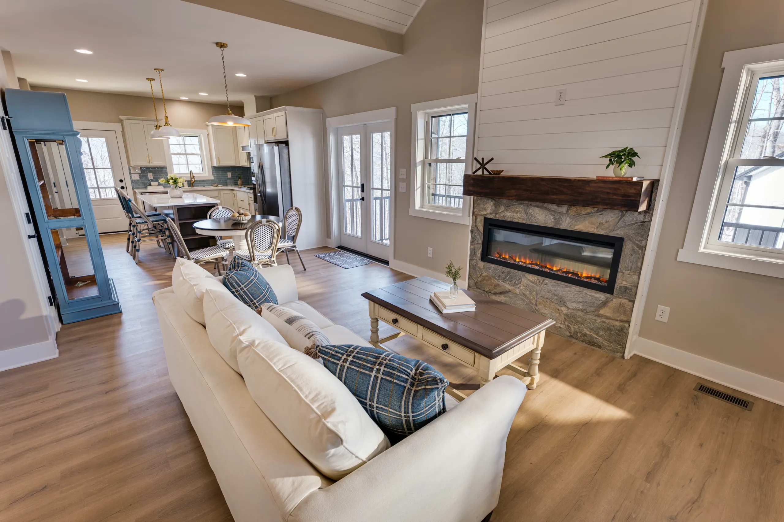 Living room with stone fireplace and open kitchen in the Reservoir Home