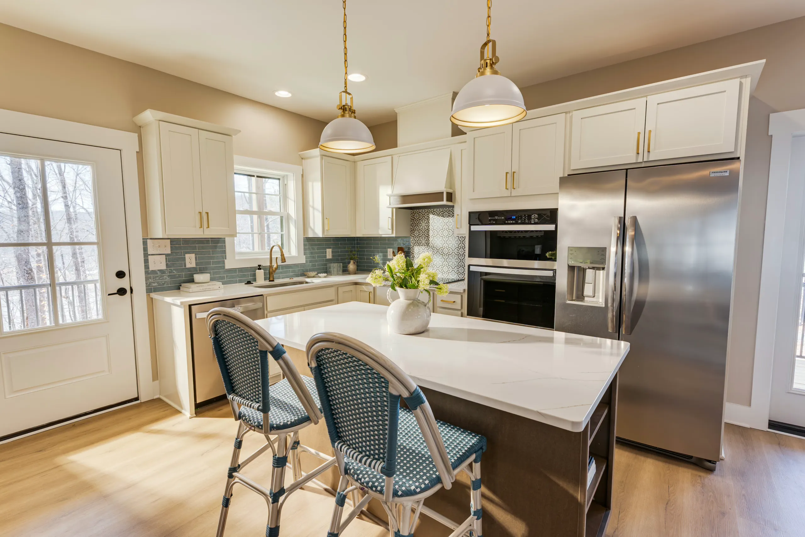 Kitchen island with bar stools and brass pendant lights in the Reservoir Home