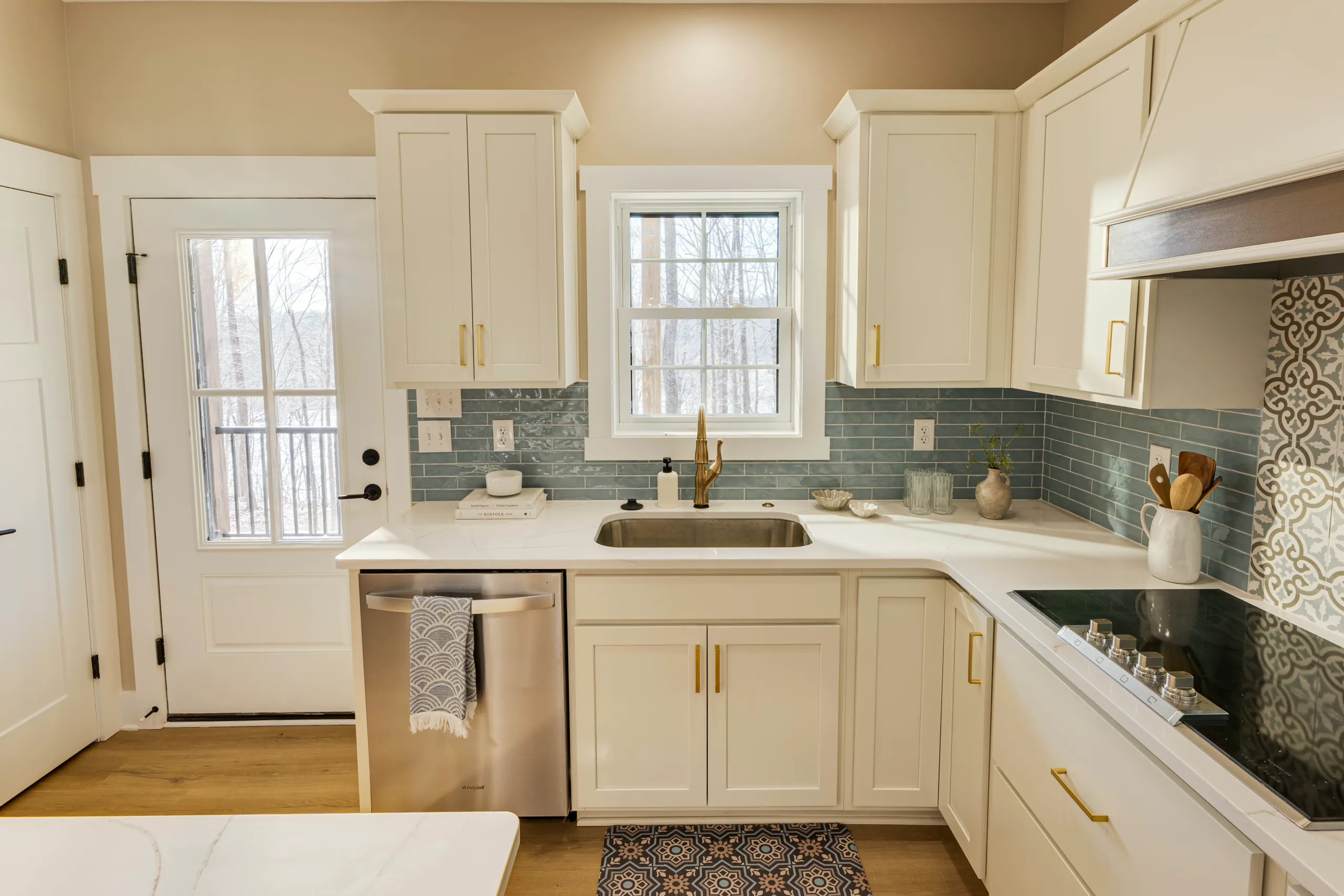 Kitchen sink with brass faucet and blue-gray tile backsplash in the Reservoir Home