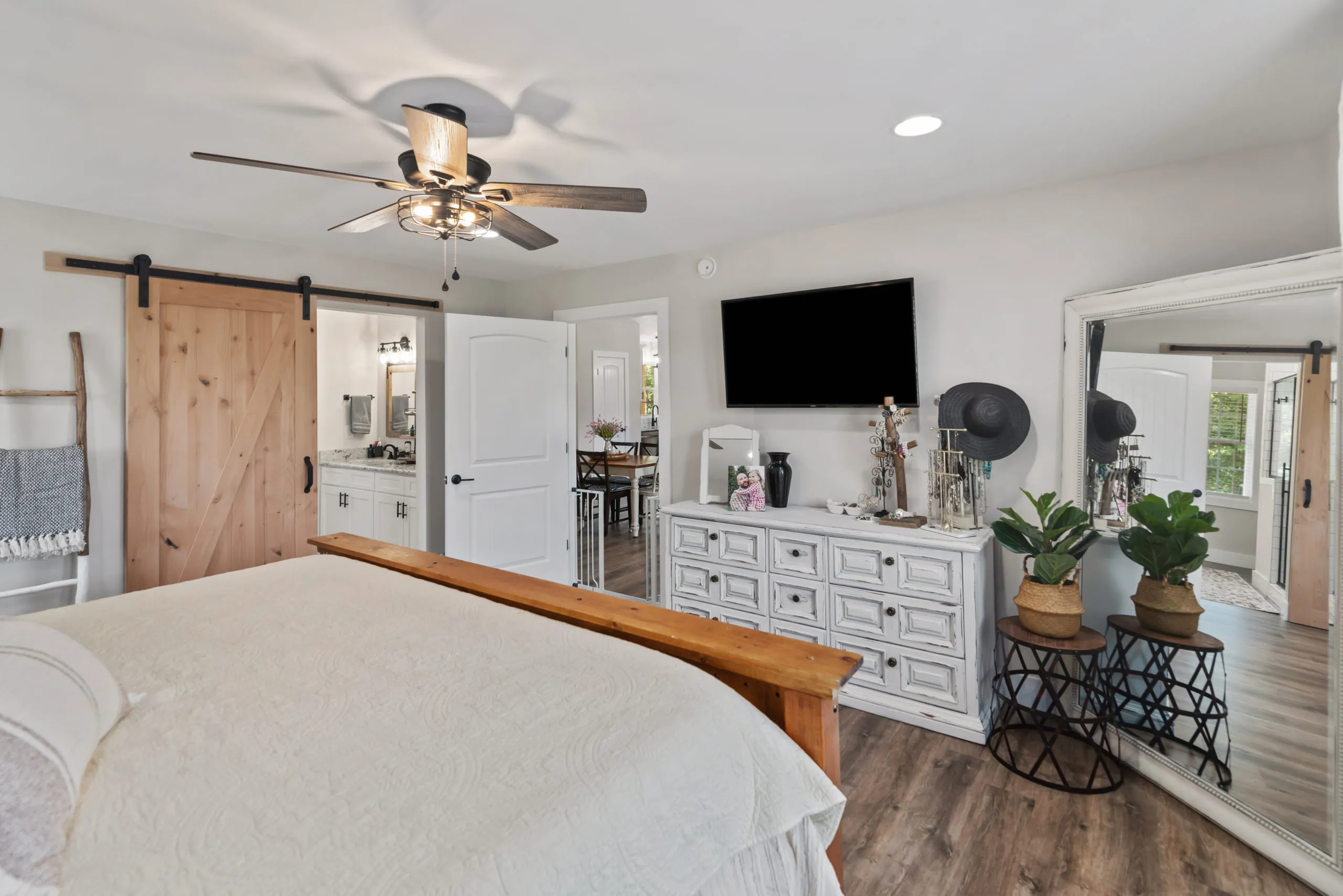 Primary bedroom with ceiling fan and barn door toward the bath in the Lake Cross Home