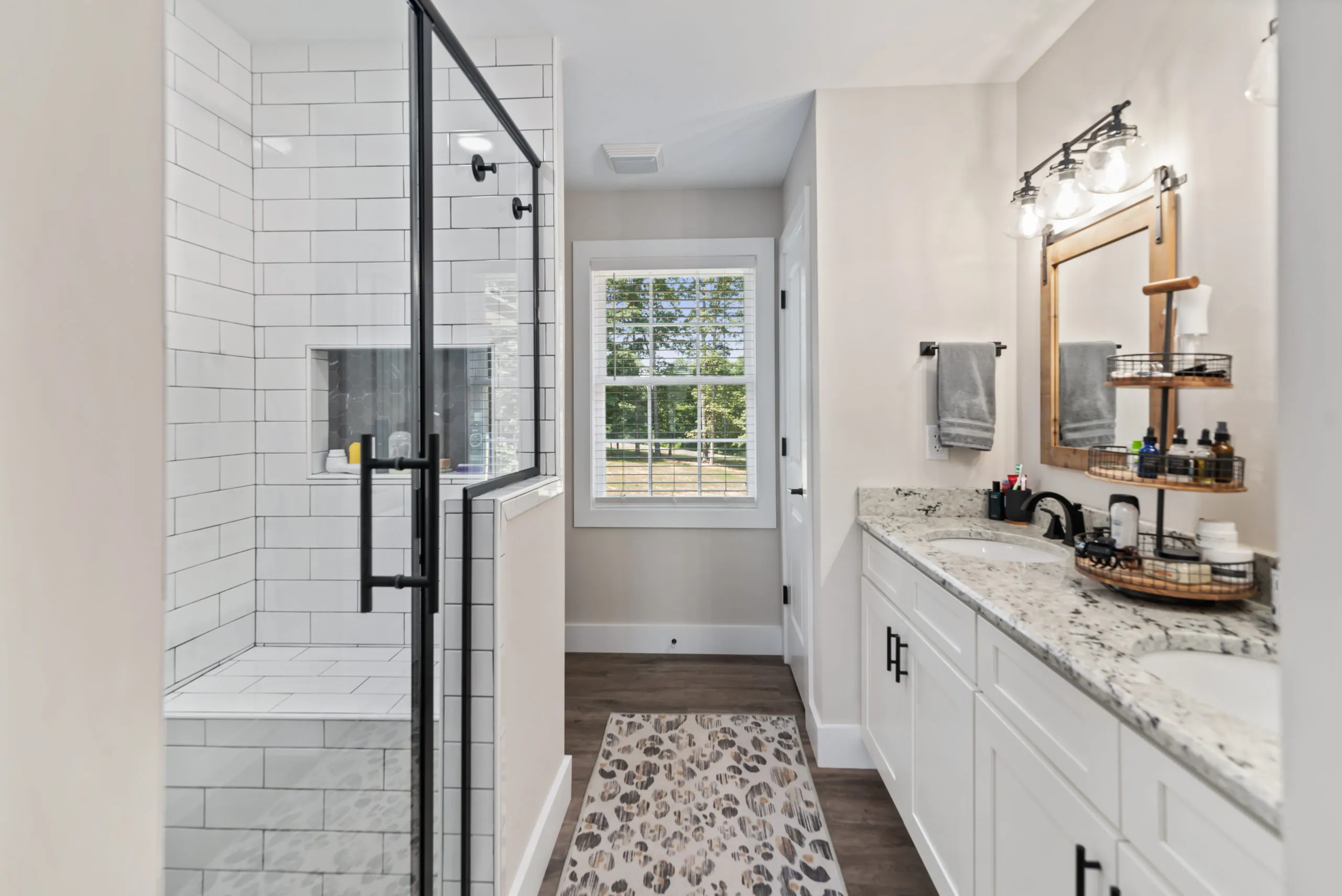Primary bathroom with granite double vanity and tiled glass shower in the Lake Cross Home
