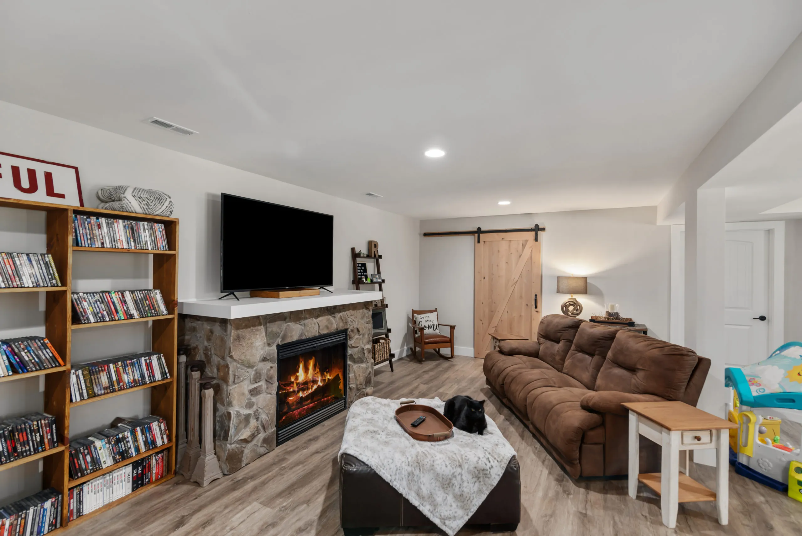 Finished basement living area with stone fireplace and barn door in the Lake Cross Home