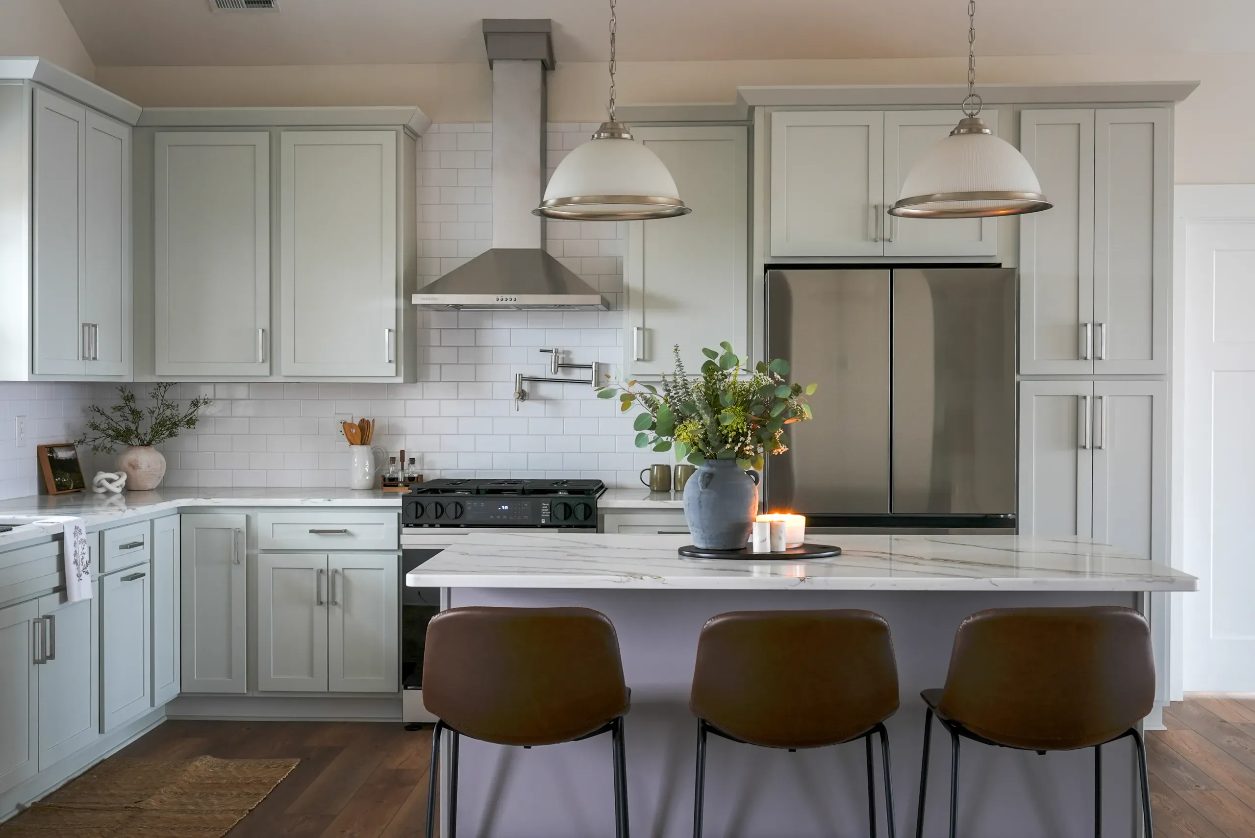 Kitchen in the Mountain Crest Home with sage cabinets, vent hood, pot filler and island