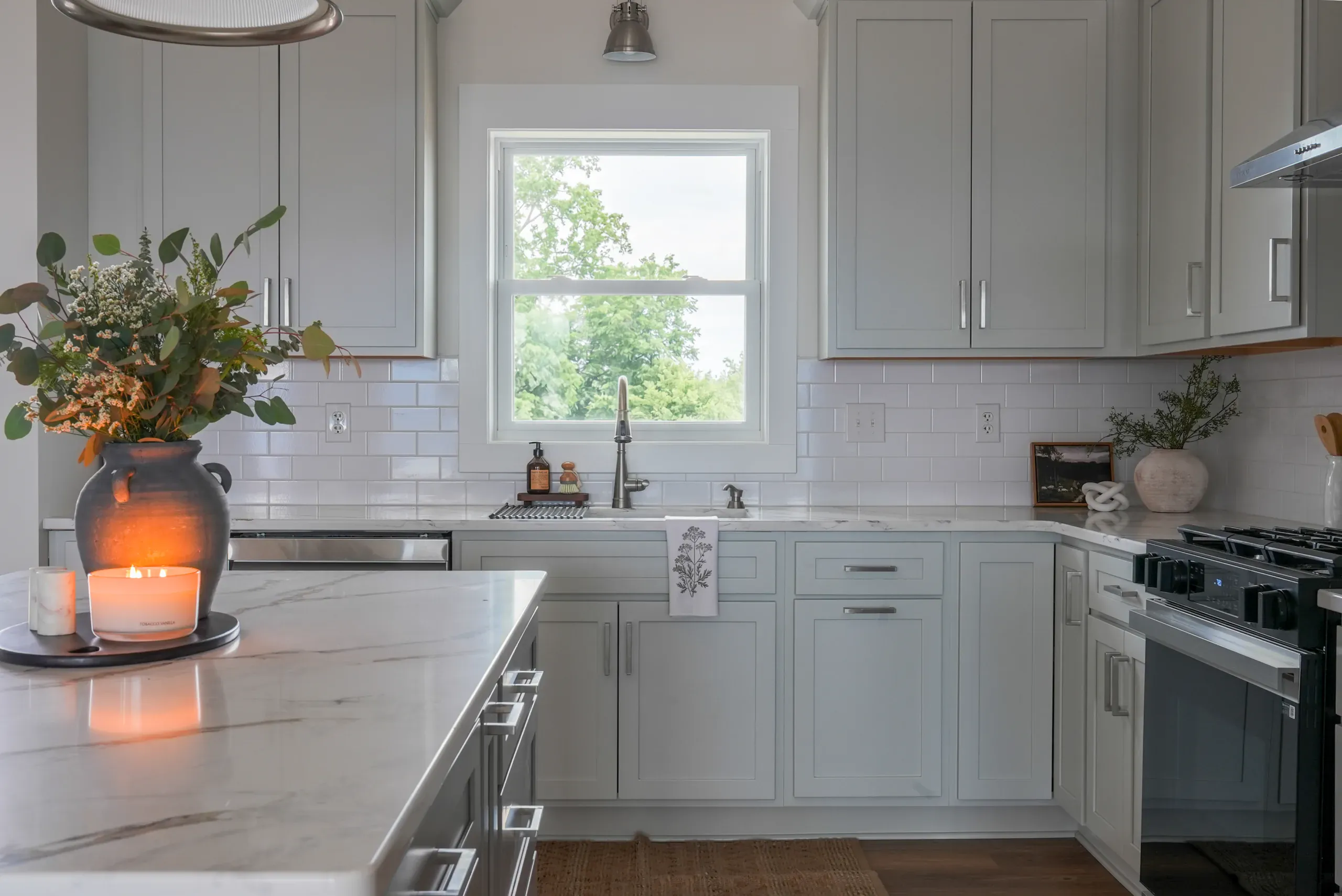 Kitchen sink under a window with gray cabinets and quartz island in the Mountain Crest Home