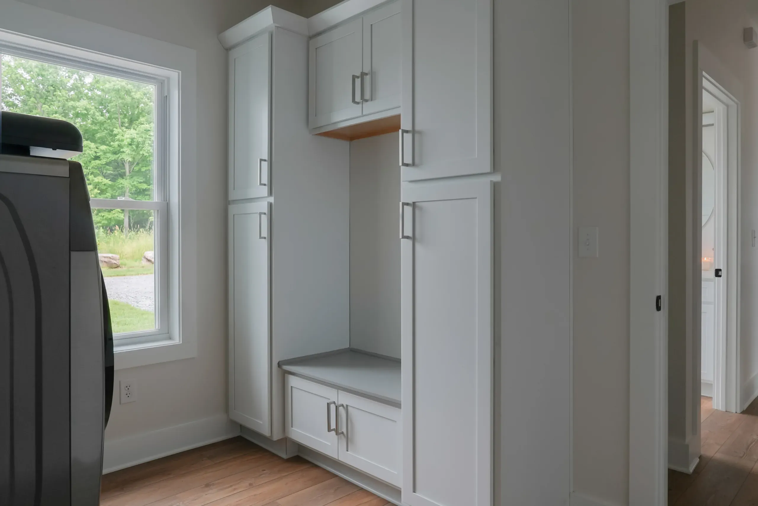 Laundry room built-in cabinets and bench beside a window in the Mountain Crest Home
