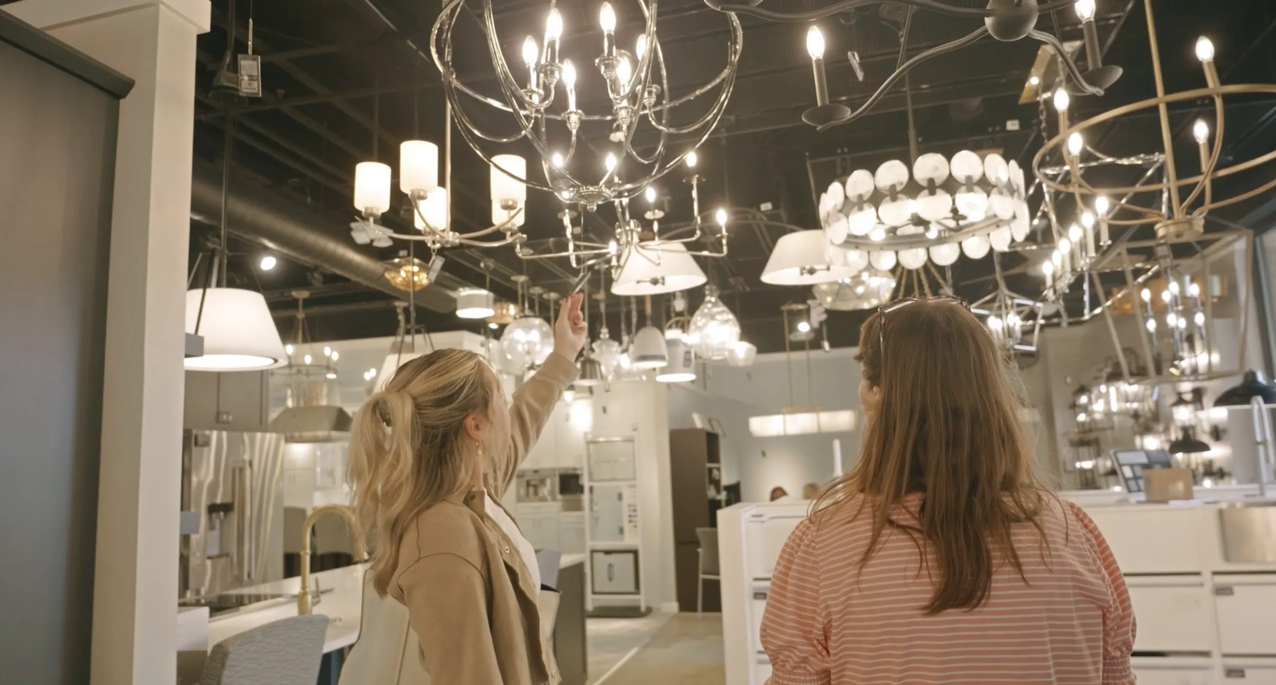 Head designer Frankie McManus showing a client different lighting fixture options in a showroom.