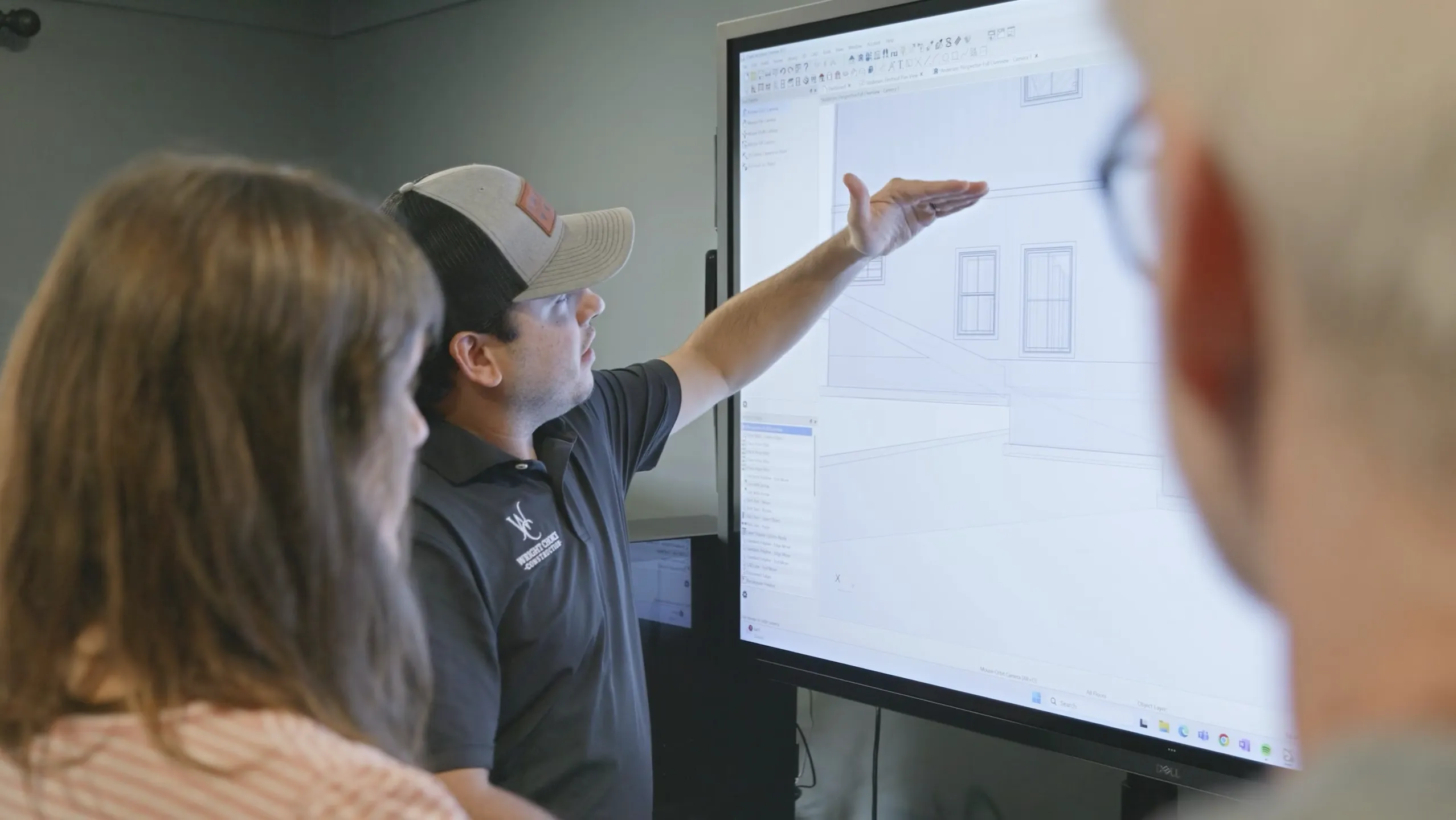 Sage Richardson showing clients their custom home plans on a large touch screen monitor.